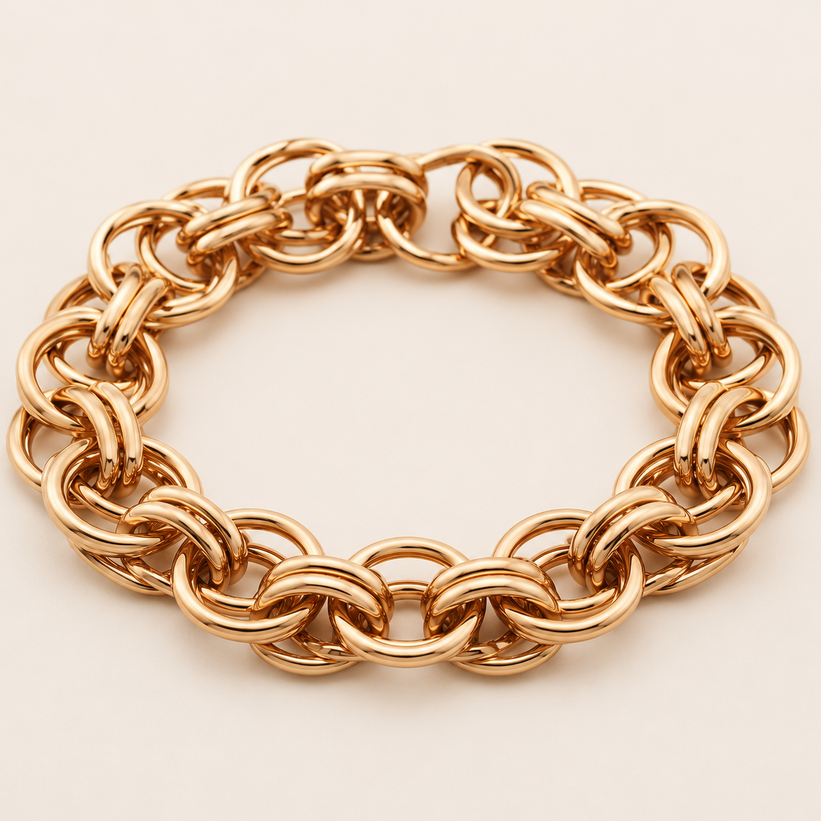 A chunky gold-tone chain link bracelet with interlocking oval links, displayed on a clean, light beige background.