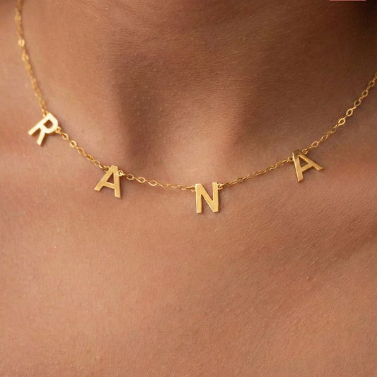 Gold necklace with 'RANIA' letters on a skin background