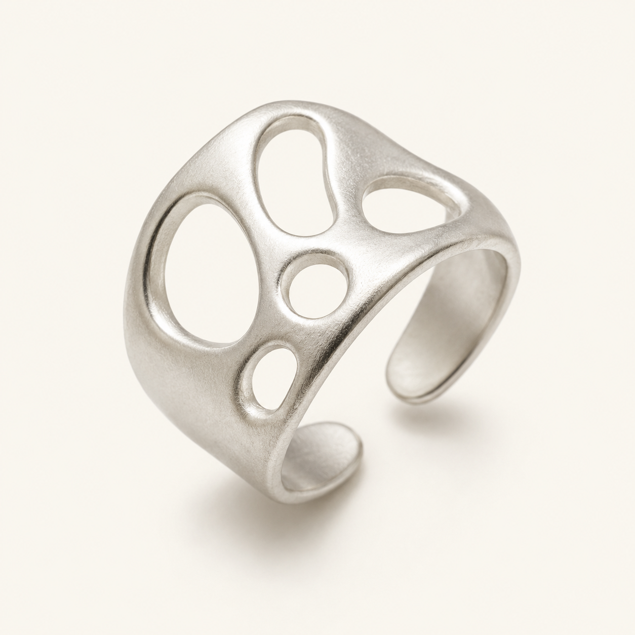 A silver open cuff ring with organic, irregular cutout shapes, photographed on a clean off-white background.