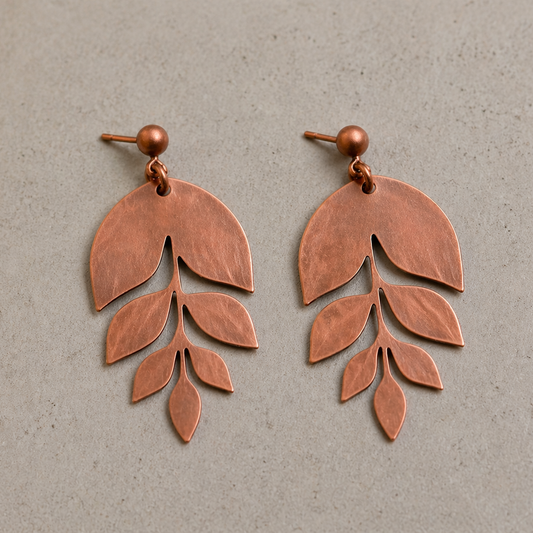 Copper leaf-shaped earrings on a gray background