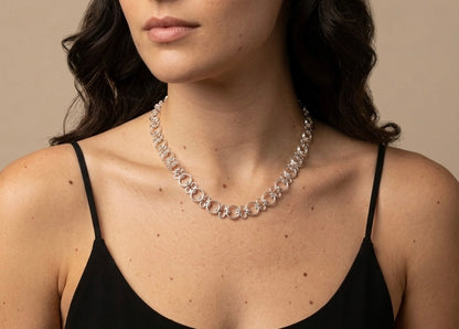 Woman wearing a silver necklace against a neutral background