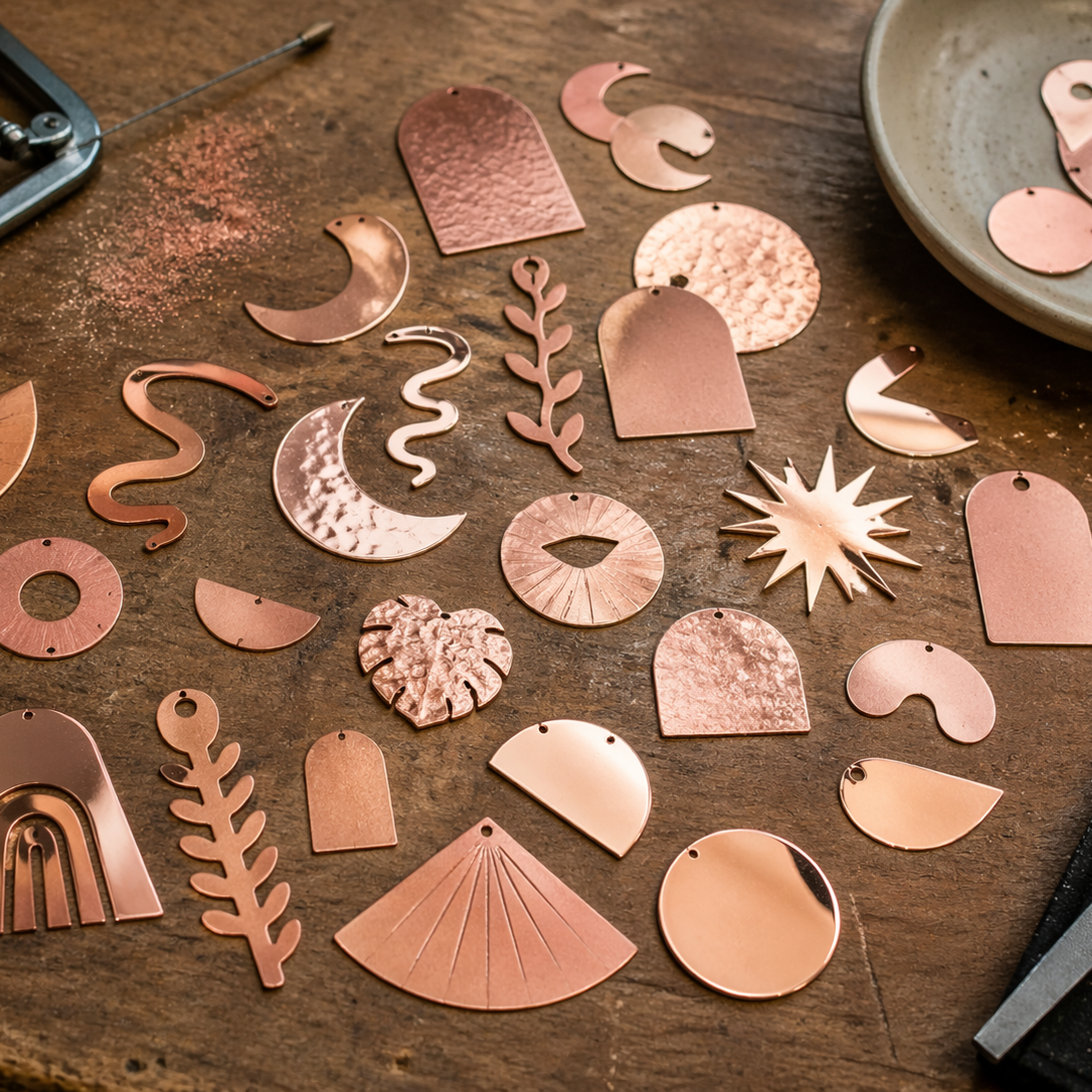 Collection of copper jewelry pieces on a wooden surface with tools.