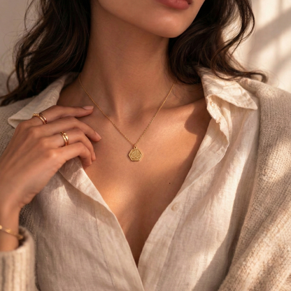 Woman wearing a gold necklace and rings with a neutral background
